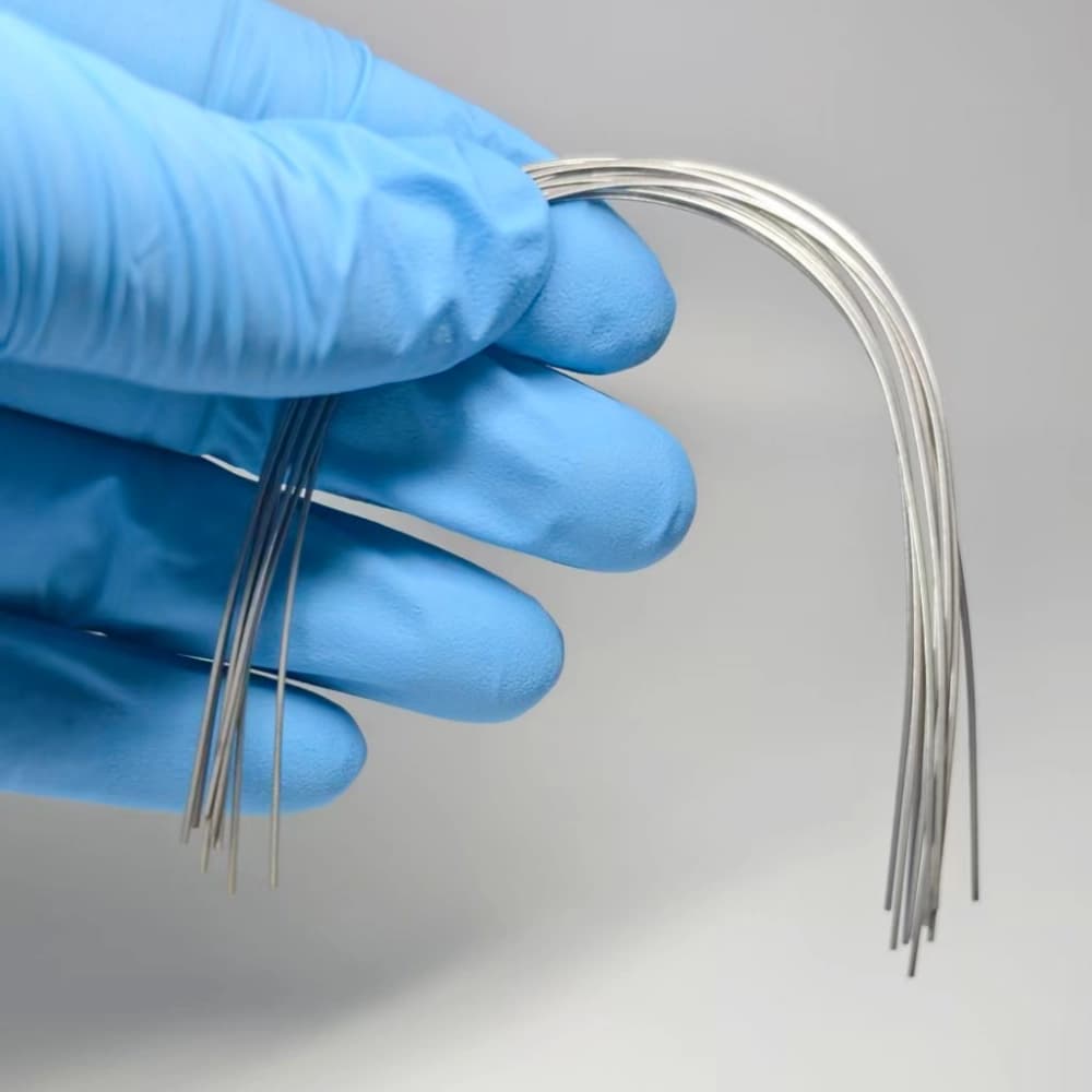 Polished stainless steel orthodontic archwires held in a gloved hand